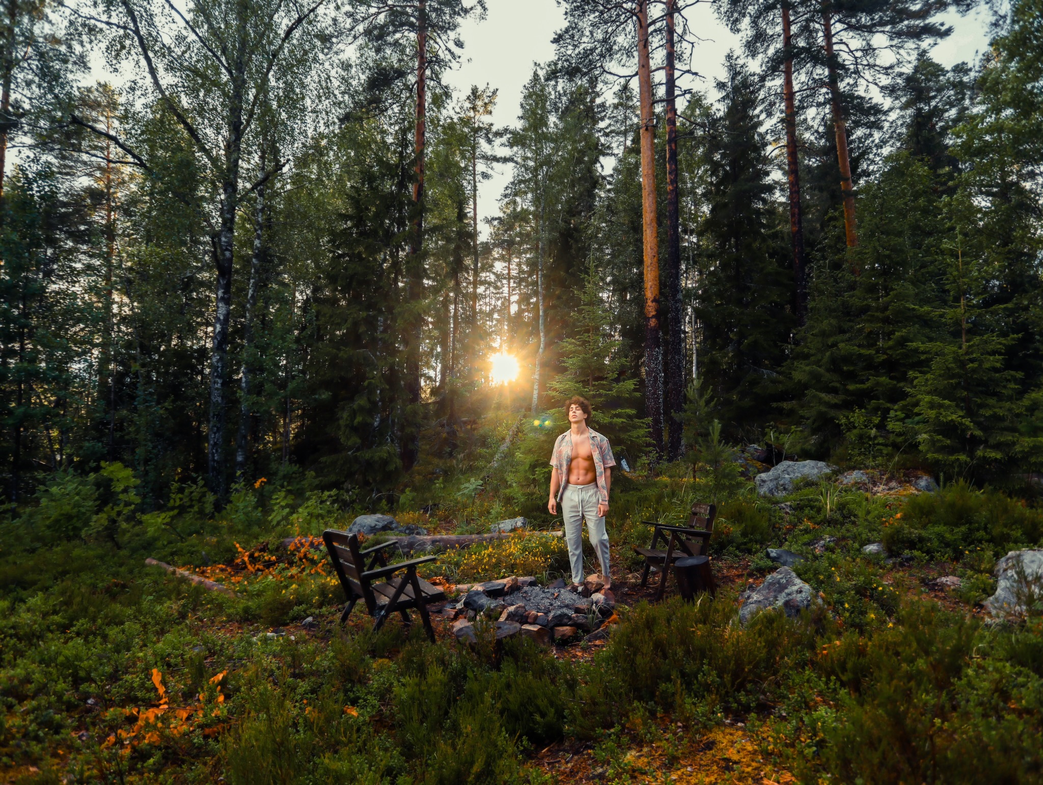 Un ragazzo è illuminato dal sole d'estate, al centro di un'isola privata solitaria nel mezzo di un lago svedese.